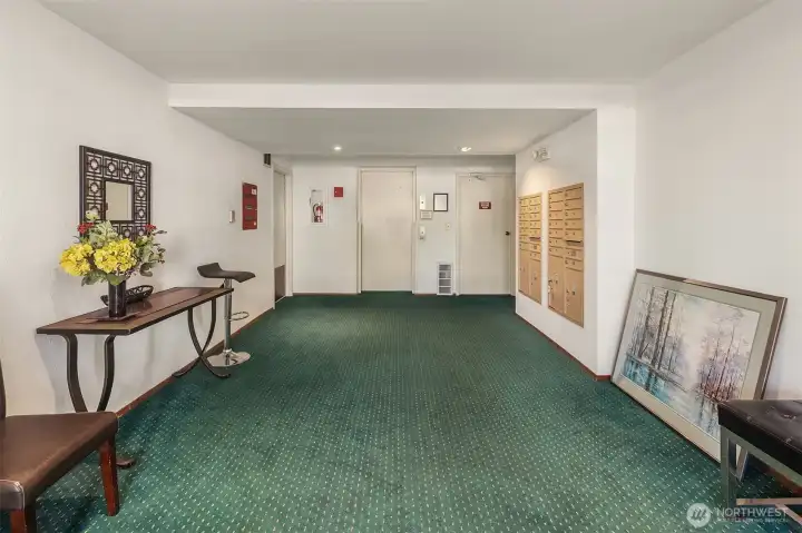 Entrance to condominium building featuring mail & elevator.