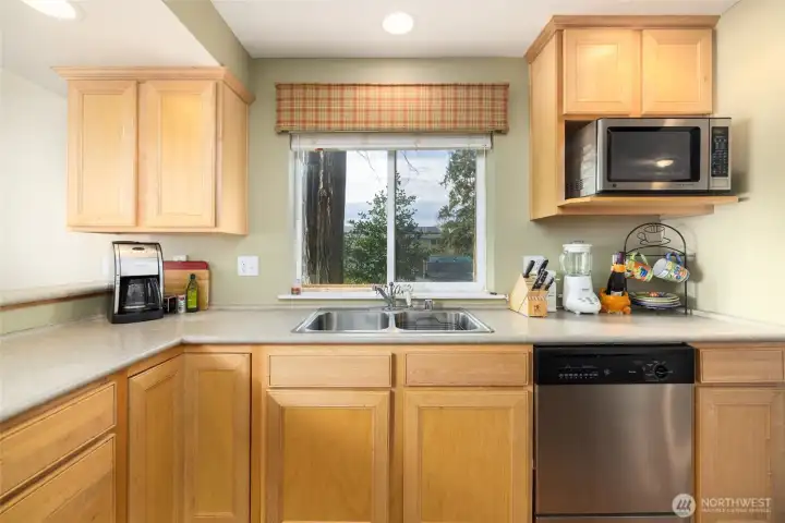 The kitchen has stainless appliances, including dishwasher, microwave, fridge, and range/oven.