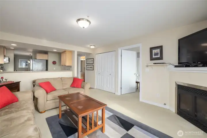 The living room, looking toward primary suite (open door, right of center), laundry closet (two closed closet doors), kitchen, and guest bath (open door, left of center).