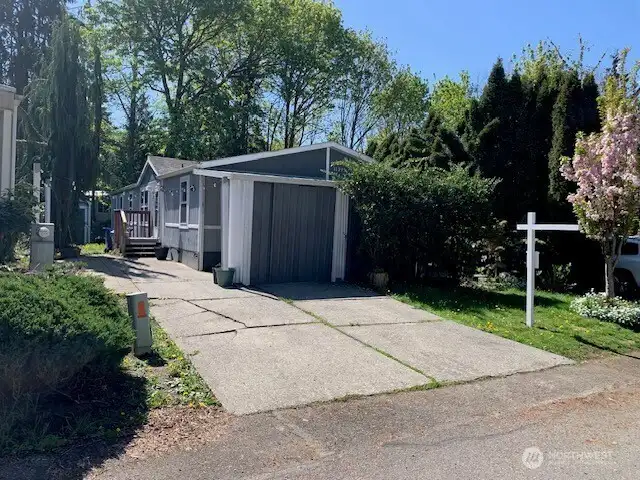 Front of unit with two off-street parking spots, covered area with shed and large patio area.