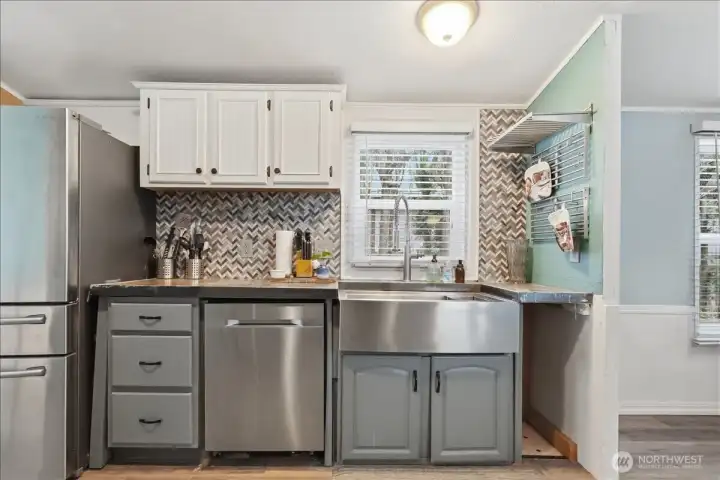 Kitchen with stainless steel appliances, farm sink and updated tile backsplash.