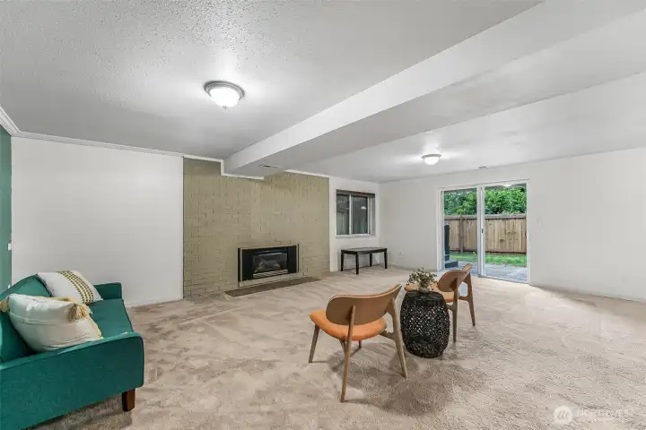 Spacious basement living area with fireplace and backyard access