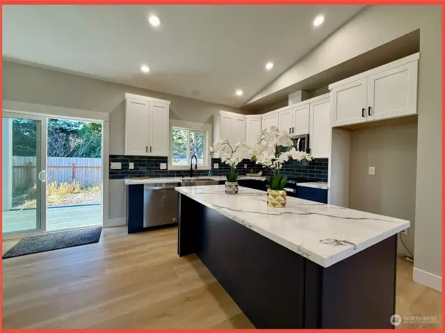 The kitchen features gorgeous cabinetry, slab Quartz counters, a farm sink, and island/breakfast bar.