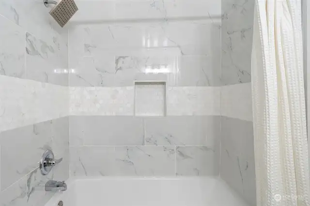 Full sized tub and glimmering tile work.