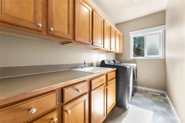 Extremely generous laundry room with an abundance of cabinets, counterspace and a sink!