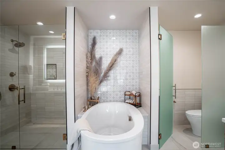 Modern jetted self-cleaning soaking tub is the focal point of the en suite primary bathroom.