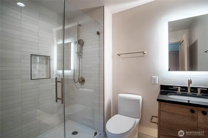 The second bedroom includes its own en suite bathroom with oversized shower and halo mirror vanity.