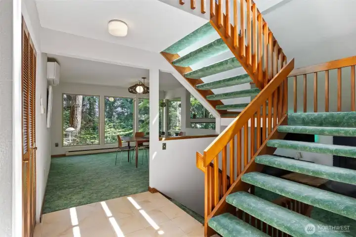 Hall with stairs to upper level and down to living room. Loft dining room in background