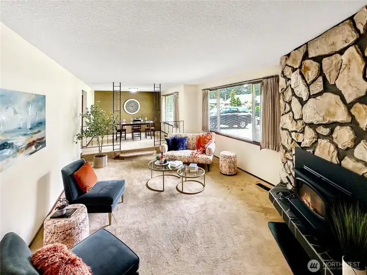 Sunken living room with large west facing window for natural light, fireplace with wood insert and stone surround.