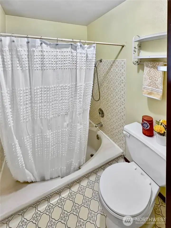 Primary Tub/shower combo with tile surround.