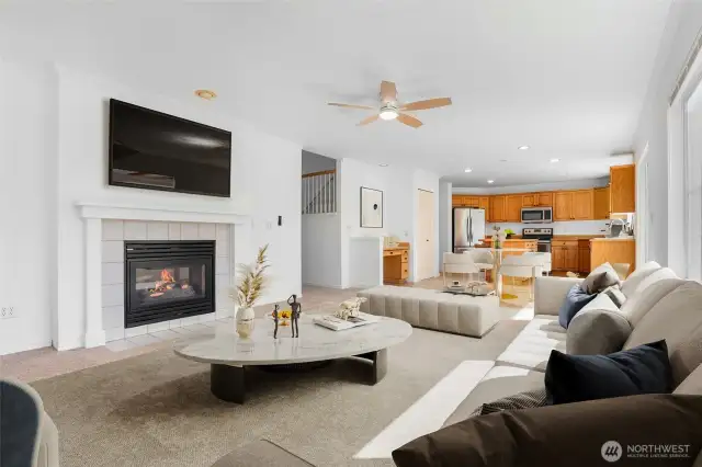 Virtually staged. Living room adjacent to kitchen with double-sided gas fireplace.