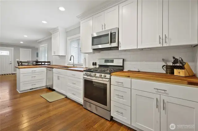 Stainless gas Range and built in microwave . light and bright kitchen butcher block counters and farm sink.