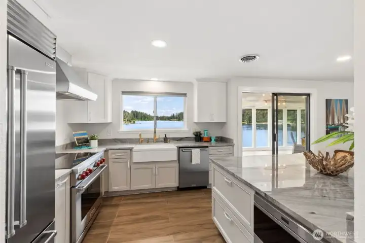 White cabinetry, premium stainless appliances, quartz surfaces and lake views in nearly every direction create a space that feels both luxurious and wonderfully livable. The farmhouse sink deserves special attention because it's positioned directly beneath a large picture window overlooking Long Lake, turning dish duty into one of the best seats in the house. A brushed gold pull-down faucet adds a designer touch, while multiple prep areas allow several people to work comfortably at once, whether you're preparing a holiday feast or putting together appetizers for a waterfront gathering. Between the Wolf appliances, Sub-Zero refrigerator and those ever-present water views, this kitchen delivers a little daily magic every time you walk into it. White cabinetry, premium stainless appliances, quartz surfaces and lake views in nearly every direction create a space that feels both luxurious and wonderfully livable. The farmhouse sink deserves special attention because it's positioned directly beneath a large picture window overlooking Long Lake, turning dish duty into one of the best seats in the house. A brushed gold pull-down faucet adds a designer touch, while multiple prep areas allow several people to work comfortably at once, whether you're preparing a holiday feast or putting together appetizers for a waterfront gathering. Between the Wolf appliances, Sub-Zero refrigerator and those ever-present water views, this kitchen delivers a little daily magic every time you walk into it.