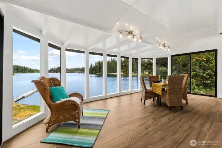 Surrounded by a dramatic wall of floor-to-ceiling glass, this incredible sunroom delivers the kind of lake views that stop people mid-sentence. The perspective from here feels almost suspended above the water, with sweeping views extending down the length of Long Lake and a front-row seat to spectacular eastern sunrises. Rich luxury vinyl plank flooring keeps the space beautiful and practical, while the sliding glass door creates an easy connection to the deck outside. Whether it's morning coffee, afternoon reading, evening wine or simply watching the weather roll across the water, this room has a way of making ordinary moments feel a little extraordinary. Fair warning: once you sit down here, you may not get much else done. Surrounded by a dramatic wall of floor-to-ceiling glass, this incredible sunroom delivers the kind of lake views that stop people mid-sentence. The perspective from here feels almost suspended above the water, with sweeping views extending down the length of Long Lake and a front-row seat to spectacular eastern sunrises. Rich luxury vinyl plank flooring keeps the space beautiful and practical, while the sliding glass door creates an easy connection to the deck outside. Whether it's morning coffee, afternoon reading, evening wine or simply watching the weather roll across the water, this room has a way of making ordinary moments feel a little extraordinary. Fair warning: once you sit down here, you may not get much else done.