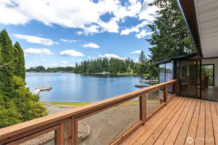 This is the kind of deck that earns its keep. Positioned directly off the sunroom, it extends your living space outdoors while keeping the focus exactly where it belongs: on the lake. Clear panel railing inserts preserve the view without visual interruption, allowing you to take in the full sweep of Long Lake, your private dock and the beautifully landscaped waterfront below. From here, you can watch boats drift by, keep an eye on swimmers and paddlers or simply enjoy the changing colors reflected across the water throughout the day. The hardscaped patio below creates an additional gathering area closer to the shoreline, giving the property multiple layers of outdoor living that feel thoughtfully connected from house to lake. This is the kind of deck that earns its keep. Positioned directly off the sunroom, it extends your living space outdoors while keeping the focus exactly where it belongs: on the lake. Clear panel railing inserts preserve the view without visual interruption, allowing you to take in the full sweep of Long Lake, your private dock and the beautifully landscaped waterfront below. From here, you can watch boats drift by, keep an eye on swimmers and paddlers or simply enjoy the changing colors reflected across the water throughout the day. The hardscaped patio below creates an additional gathering area closer to the shoreline, giving the property multiple layers of outdoor living that feel thoughtfully connected from house to lake.