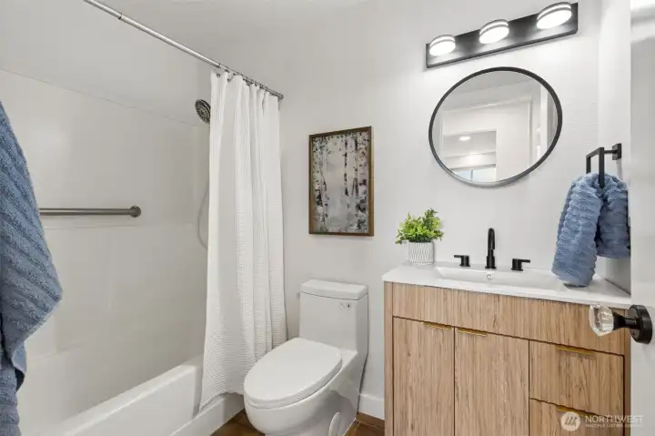 The renovation story continues in this beautifully updated bathroom, where nearly every surface has been refreshed to create a clean, contemporary feel. A sleek warm-toned vanity brings natural texture and character to the space while providing practical storage below, pairing beautifully with crisp white walls and updated fixtures throughout. Dark ceramic tile flooring grounds the room with rich contrast and durability and a new toilet and updated finishes complete the transformation. And having a 3rd shower in the full tub shower surround, is like pure gold for kids, grandkids and guests. The convenience of a 3rd shower changes things in a good way. The renovation story continues in this beautifully updated bathroom, where nearly every surface has been refreshed to create a clean, contemporary feel. A sleek warm-toned vanity brings natural texture and character to the space while providing practical storage below, pairing beautifully with crisp white walls and updated fixtures throughout. Dark ceramic tile flooring grounds the room with rich contrast and durability and a new toilet and updated finishes complete the transformation. And having a 3rd shower in the full tub shower surround, is like pure gold for kids, grandkids and guests. The convenience of a 3rd shower changes things in a good way.