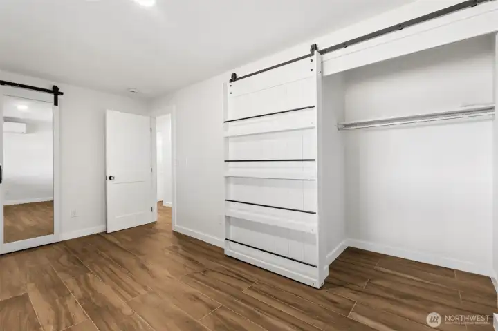 This lower-level bedroom proves that practical can still be clever. In addition to its spacious layout and fresh updates, you'll find an innovative storage solution with sliding closet doors featuring built-in shelving, making great use of every inch of space. In fact, this room offers not one but two closets, providing flexibility for clothing, hobbies, seasonal storage or guest accommodations. Luxury vinyl plank flooring continues throughout, bringing durable beauty and easy maintenance, while crisp white walls keep the room feeling bright and inviting. Located on the lower level alongside the additional bedrooms, this space offers privacy away from the primary suite upstairs, making it an excellent option for guests, multigenerational living or a dedicated office setup. This lower-level bedroom proves that practical can still be clever. In addition to its spacious layout and fresh updates, you'll find an innovative storage solution with sliding closet doors featuring built-in shelving, making great use of every inch of space. In fact, this room offers not one but two closets, providing flexibility for clothing, hobbies, seasonal storage or guest accommodations. Luxury vinyl plank flooring continues throughout, bringing durable beauty and easy maintenance, while crisp white walls keep the room feeling bright and inviting. Located on the lower level alongside the additional bedrooms, this space offers privacy away from the primary suite upstairs, making it an excellent option for guests, multigenerational living or a dedicated office setup.