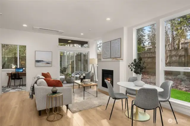 Step into the heart of the home—a cozy yet airy living room bathed in natural light. The fireplace creates a warm focal point, while large windows bring the lush outdoors inside.