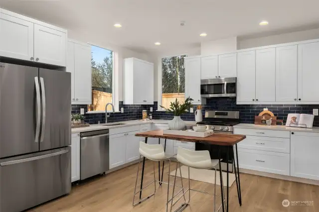 A culinary haven awaits with this stunning kitchen. This space blends functionality with modern design, featuring a sleek stainless steel appliance and a chic navy tile backsplash. Perfect for casual meals or hosting with style.