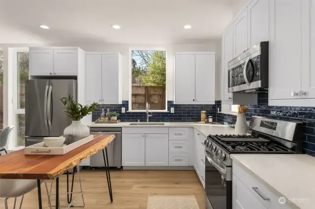 Light streams into the heart of the home, showcasing pristine white cabinetry and bold design elements. The spacious layout and high-end finishes make this kitchen a chef’s dream and an entertainer’s delight.