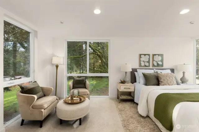 Step into tranquility in the main-level primary suite. Large windows bring the outdoors in, creating a serene atmosphere complemented by cozy seating and calming decor—a private escape with style and comfort.