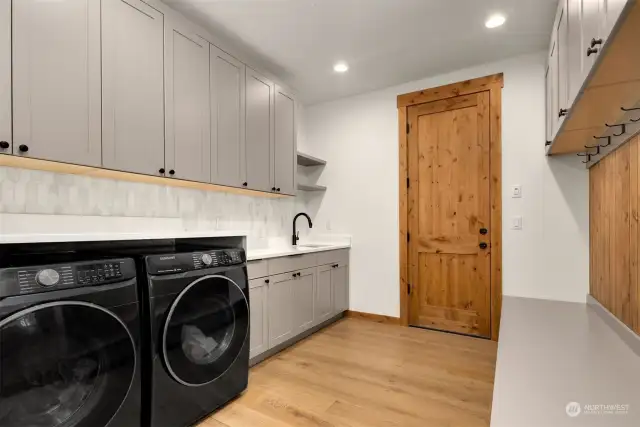 Mudroom with handwashing sink, built in washer and dryer with folding counter top above, ample cabinets and so much storage in this home!