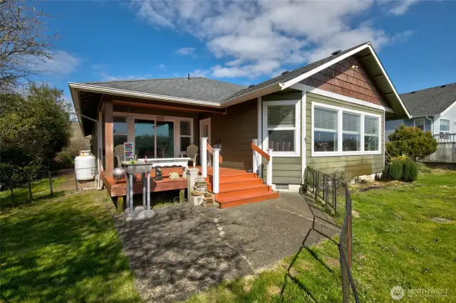 In the back yard, there is a large covered deck and a patio area.