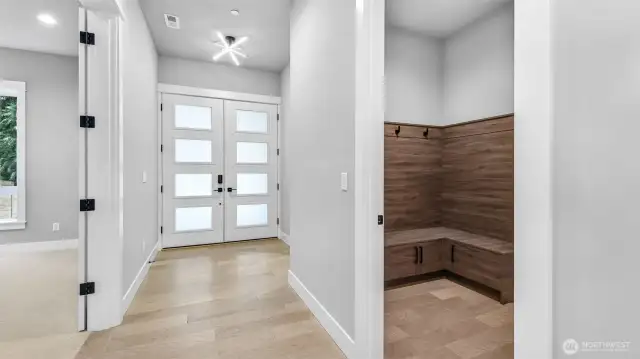 Upon entering through the front double doors, you have the den to your left, a powder room to the right, as well as a mud room and access to the garage (in this photo).
