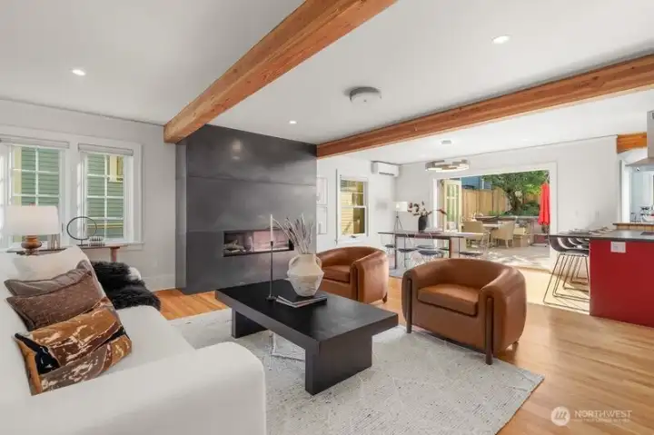 Spectacular great room features a stunning blackened steel encasement surrounding the gas fireplace, gorgeous hardwood floors, beautiful wood beams, dining room and tri-fold doors that spill out to the entertainment deck.