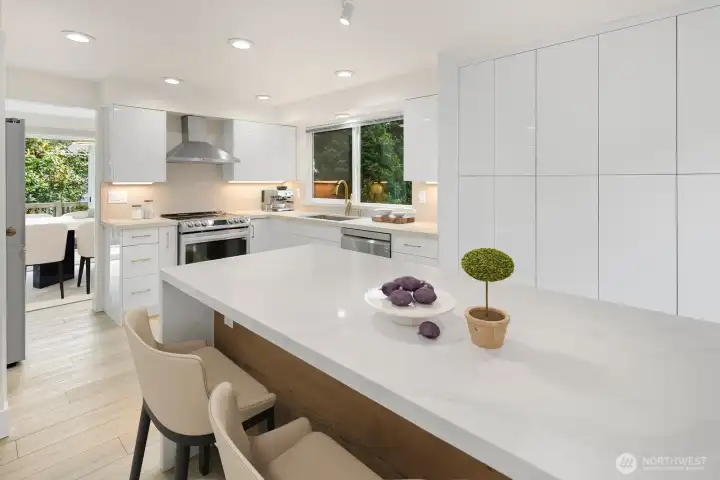 Curated Contemporary Kitchen Renovation Featuring Expansive Slab Quartz Waterfall Island with Seating and Sleek Modern Cabinetry - Virtually Staged