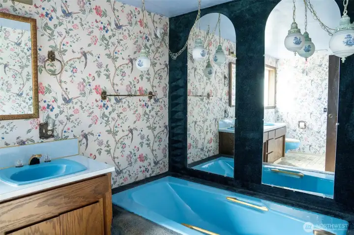 A deep blue soaking tub, gold accents, floral globe lighting, and graceful arched mirrors make this bathroom unforgettable. A deep blue soaking tub, gold accents, floral globe lighting, and graceful arched mirrors make this bathroom unforgettable.