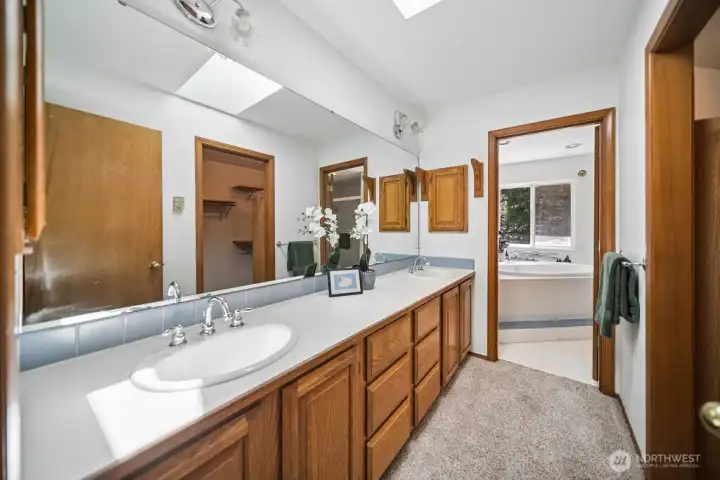 Double vanity and walk in closet to right, bath and shower in private area  separated by a door.