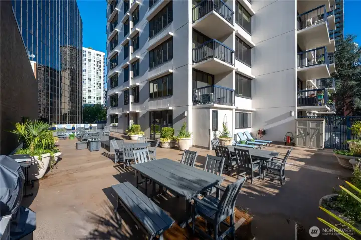 Pool deck off clubhouse w/ lawn chairs, outdoor seating/couches. gas firepit and BBQ's.