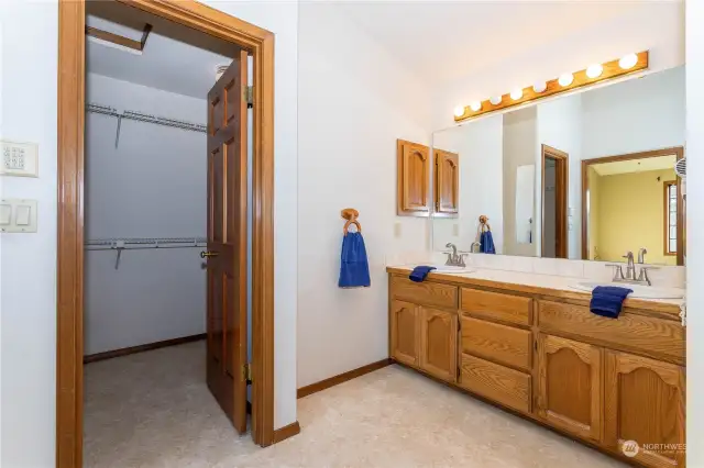 Oversized walk-in-closet of primary suite and double-sinks of vanity