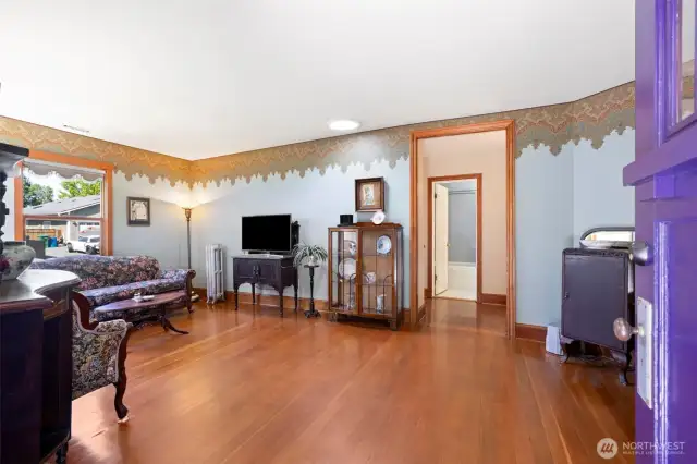 Light-filled living room showcases original hardwood floors, beautiful custom baseboards, and timeless architectural charm.