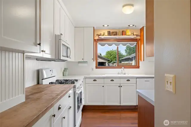 Warm butcher block counters and tall cupboards offer beauty and function in this inviting kitchen.