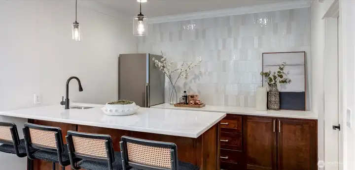 Exquisite full bar is the heart of the lower level! Stunning light and bright quartzite counters create a striking focal point, while curated tiling adds a touch refinement.