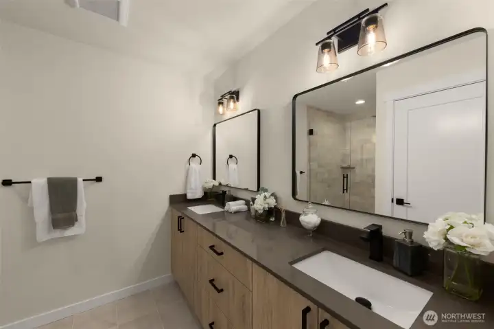 The primary bath feels like a five-star spa! Complete with sleek dual vanities, contemporary lighting, and a soothing palette of stone and glass.