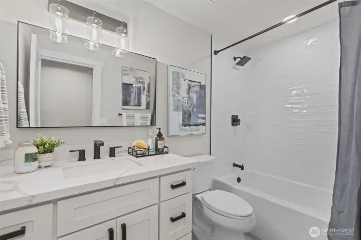 Remodeled full bath with quartz vanity, subway tile surround, and modern black fixtures for a fresh, contemporary feel.