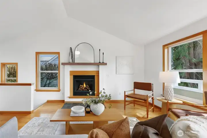 Oak hardwoods shine under vaulted ceilings lit by abundant natural light pouring in through east, south, and west windows.