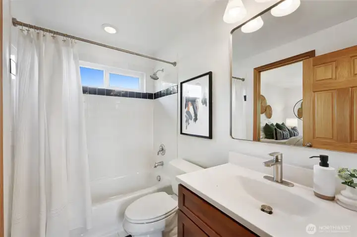 Bright and cheery ensuite bath off of the primary bedroom is also connected to the hallway for guests.