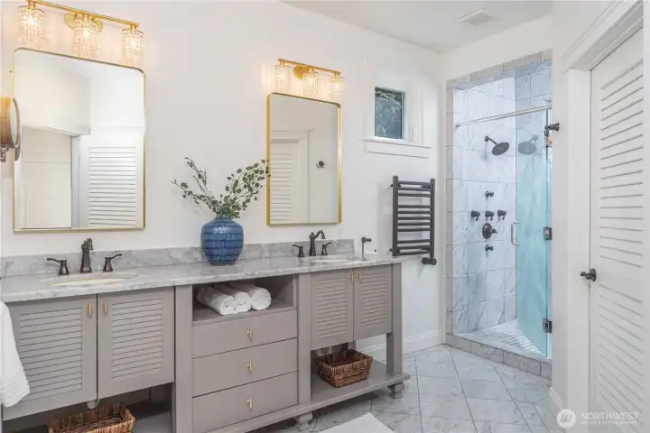 The primary bathroom has dual sinks, heated marble floors, a spacious shower with mulitple shower heads, private water closet and built-in linen closet.