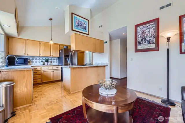 The open-design kitchen is appointed with gorgeous slab granite counters, customized oak cabinets with pull-outs, a newer Samsung fridge, GE Profile dishwasher, and a STL range.