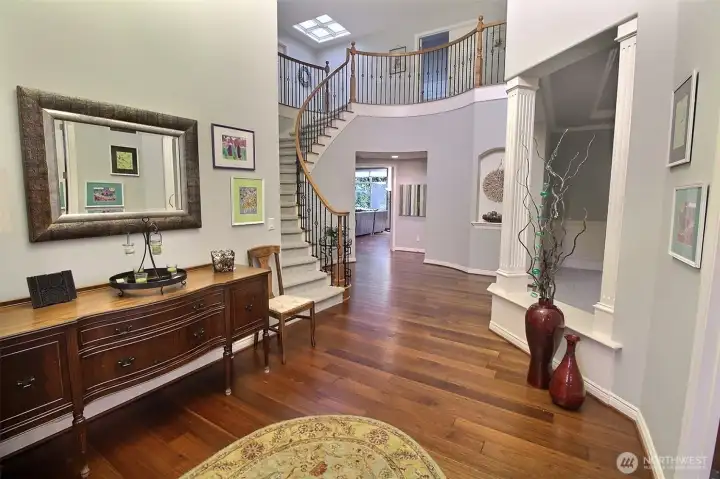 A Grand Entry with 2-Story tall entry, nice design features, curved Staircase, Iron Balusters, curved walls, stylish pillars and a full engineered floor.