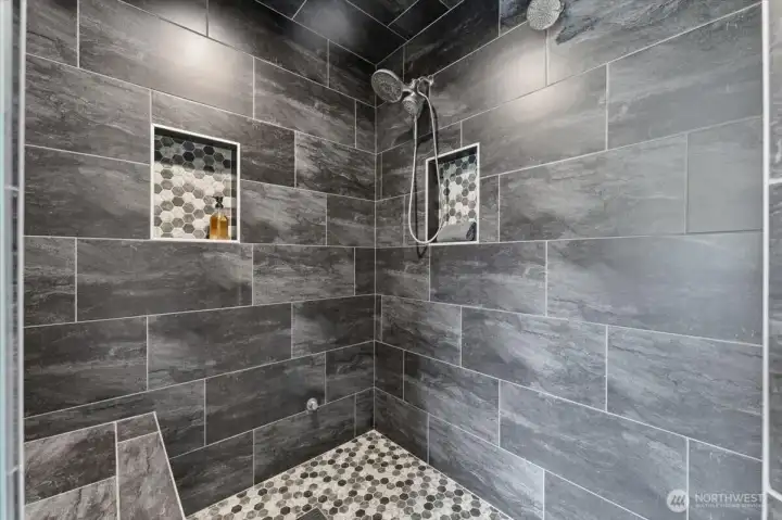 Third-floor primary bath with an expansive, beautifully tiled shower.