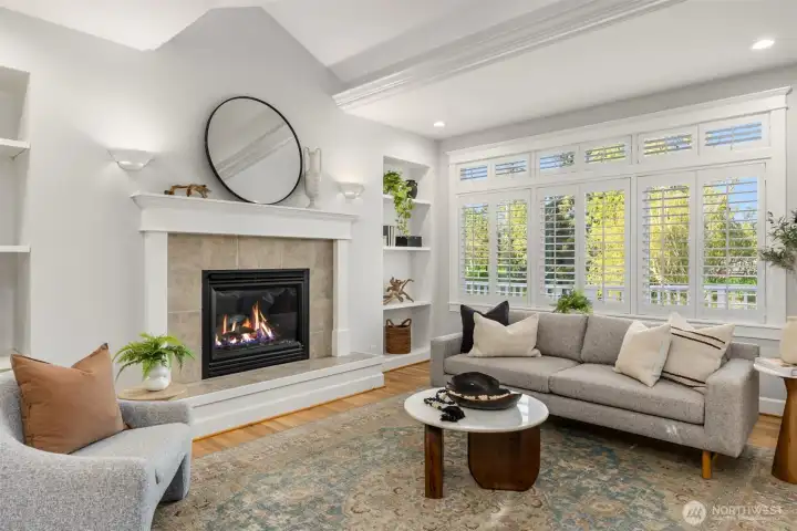 The main living room has vaulted ceilings with recessed lighting, built-in bookshelves surrounding the propane fireplace and pretty views out to the course.