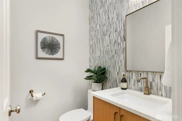 The stylish half bathroom with high end fixtures, solid wood cabinetry and a fabulous tiled accent wall.