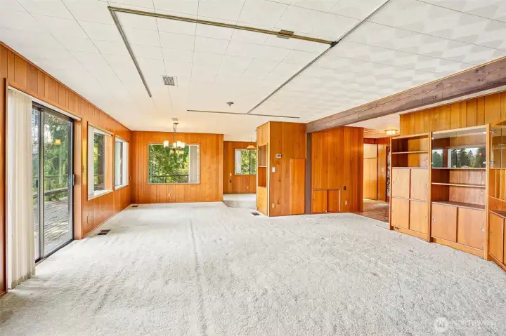 Living room with built-ins, ceiling beam, and slider to back deck overlooking Lake Tapps.