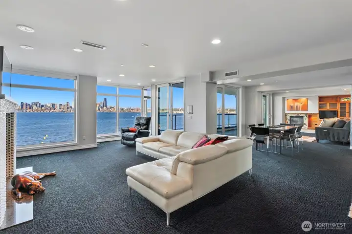 From the living room, the sightline flows effortlessly into the dining area, where large glass doors open to an expansive view deck that spans a significant portion of the home. This outdoor space extends your living area and offers the perfect setting for dining al fresco or relaxing above the shoreline. From here, take in truly breathtaking panoramas of the Seattle skyline, the Cascade Mountains, and the ever-changing waters of Puget Sound—an unforgettable backdrop for both everyday living and special occasions.