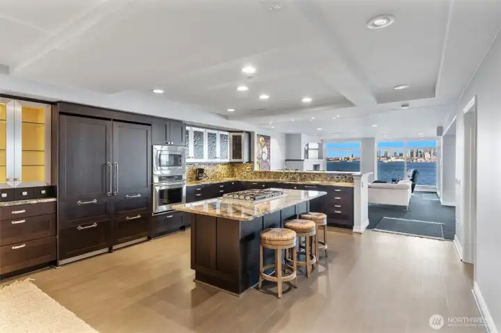 The updated kitchen features warm cork flooring and a seamless blend of style and function, including side-by-side Sub-Zero refrigerator and freezer with custom paneled fronts, illuminated cabinetry, and a 5-burner gas cooktop. Most notably, the space is perfectly positioned to capture uninterrupted, open views of the city skyline and Puget Sound—bringing a stunning backdrop to everyday cooking and entertaining.